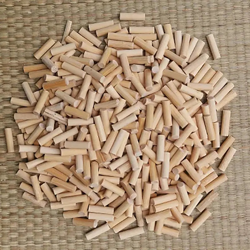 Vue de dessus d’un grand tas de mekugi en bambou clair, section ronde, extrémités majoritairement planes, posés sur un tatami tressé beige ; aucun sabre ni fourreau visible. Accessoires pour katana, mots-clés mekugi bambou katana, HEMA AMHE.
