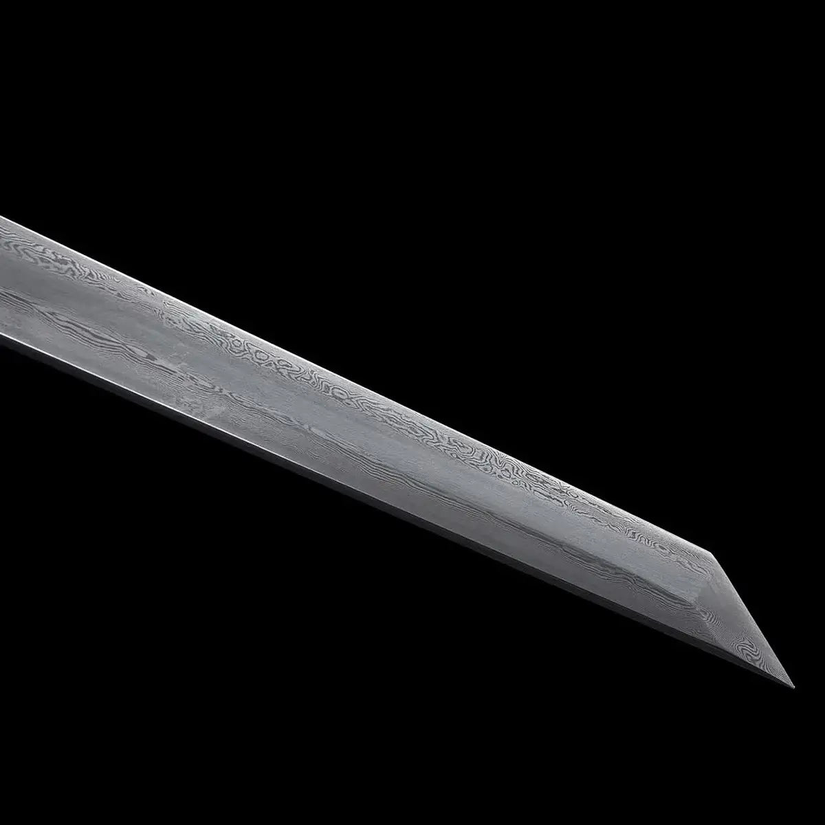 Gros plan de la lame du katana japonais ONI NO KIBA montrant l’acier plié avec motifs visibles et une pointe angulaire de type kiriha-zukuri, sans fourreau ni poignée visibles, fond noir.
