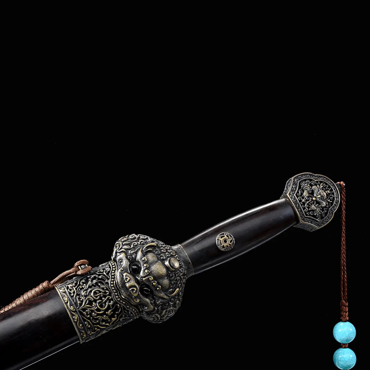 Détail de la poignée et du fourreau d’une épée chinoise Jian Longquan, avec bois sombre type ébène, garde métallique ornementée, pommeau décoré, cordon brun et perles turquoise sur fond noir.
