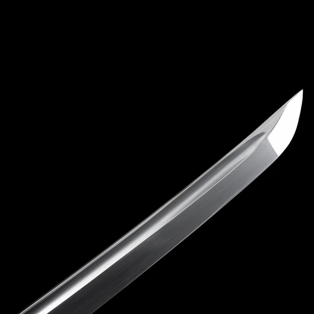 Close-up detail of the Ryusei Japanese katana blade tip photographed against a solid black background. The polished 1060 carbon steel blade shows a defined kissaki with a clean, sharp edge and smooth surface finish. The curvature of the blade is clearly visible, highlighting the precision of the grind and the refined geometry typical of a traditional Japanese katana.
