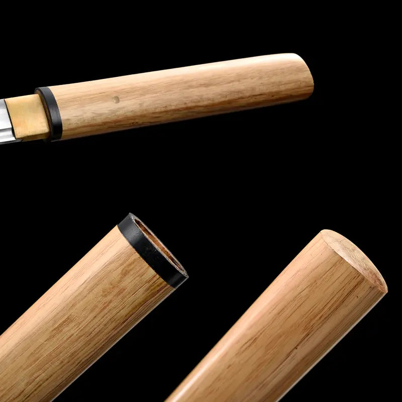 Gros plan du tantō shirasaya San-Ken : ouverture du fourreau avec bague noire, habaki en laiton et début de lame polissage miroir, bois clair veiné, composition en trois segments sur fond noir — couteau japonais acier carbone 1045, finition artisanale minimaliste.