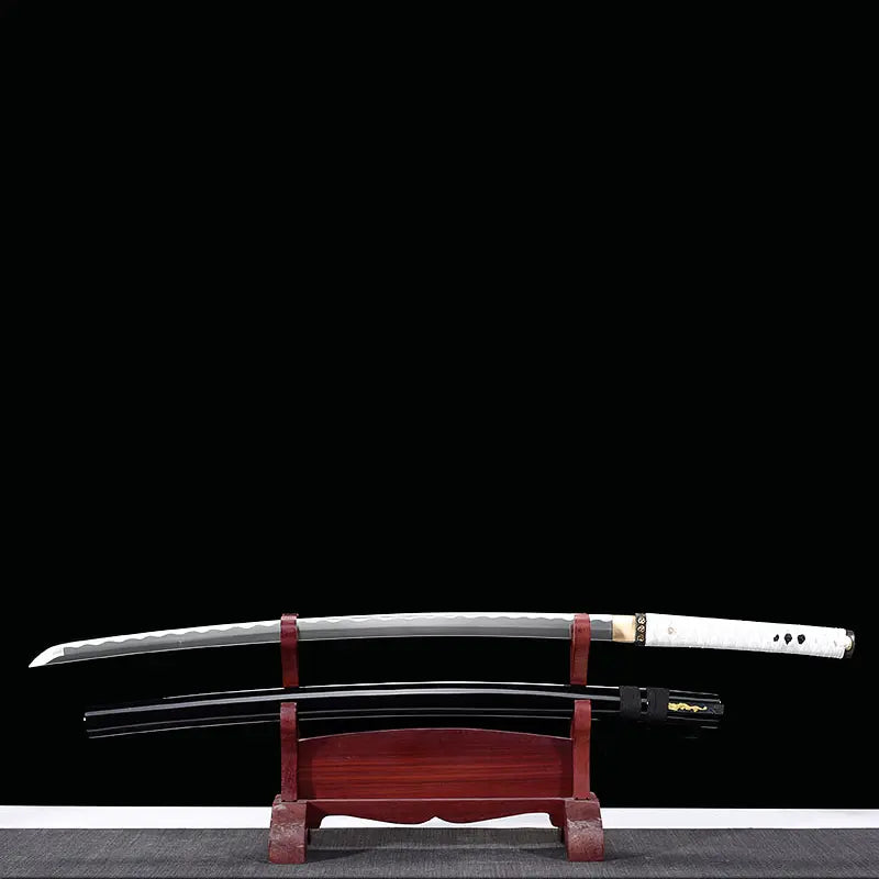 Katana japonais artisanal Shinobi no Kiba, Le Croc du Shinobi, présenté sur fond noir sur un support en bois rouge foncé avec la lame sortie du fourreau. Lame en acier carbone 1045 sans bo-hi visible au-dessus, saya noir laqué positionné en dessous avec sageo noir, tsuka en cuir blanc avec tressage ito noir, mise en scène mettant en valeur la double configuration lame et fourreau.
