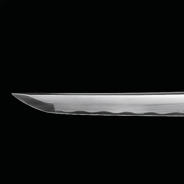 Détail de la pointe du katana japonais artisanal Shinobi no Kiba, Le Croc du Shinobi, sur fond noir. Kissaki bien définie avec courbure régulière, lame en acier carbone 1045 sans bo-hi, finition mate laissant apparaître une ligne de trempe discrète, profil épuré typique du style ninja.
