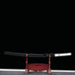 Katana japonais artisanal Shinobi no Kiba, Le Croc du Shinobi, présenté sur un support en bois rouge foncé, sur fond noir. Katana rangé dans son saya noir laqué avec sageo noir noué, tsuka en cuir blanc avec tressage ito noir, présentation horizontale mettant en valeur le profil discret et l’esthétique ninja.
