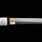 Détail de la lame du katana japonais artisanal Shinobi no Kiba, Le Croc du Shinobi, sur fond noir. Jonction entre la tsuka et la lame avec habaki doré visible, acier carbone 1045 à finition mate, lame sans bo-hi avec ligne de trempe discrète, montage sans tsuba au style ninja épuré.
