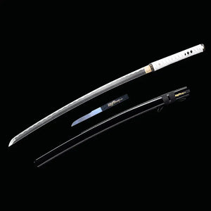 Katana japonais artisanal Shinobi no Kiba, Le Croc du Shinobi, présenté sur fond noir avec la lame principale sortie du fourreau et le kozuka exposé séparément. Lame en acier carbone 1045 sans bo-hi, tsuka en cuir blanc avec tressage ito noir, saya noir laqué posé en dessous avec sageo noir, petit couteau auxiliaire en acier inoxydable visible, illustrant la configuration à la
