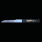 Kozuka du katana japonais artisanal Shinobi no Kiba, Le Croc du Shinobi, présenté sur fond noir. Petit couteau auxiliaire en acier inoxydable partiellement sorti de son logement, lame droite visible, manche noir avec décoration dorée en relief, intégré dans le saya noir laqué.
