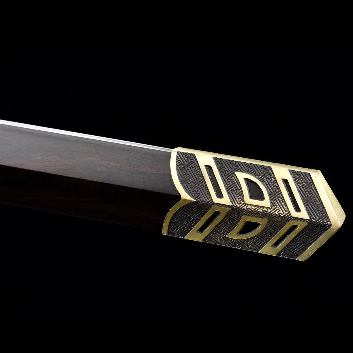 Gros plan sur l’extrémité du fourreau noir style ébène de l’épée chinoise Jian SHU SHENG, avec embout en laiton doré décoré de motifs géométriques et texture sombre gravée, présenté sur fond noir.