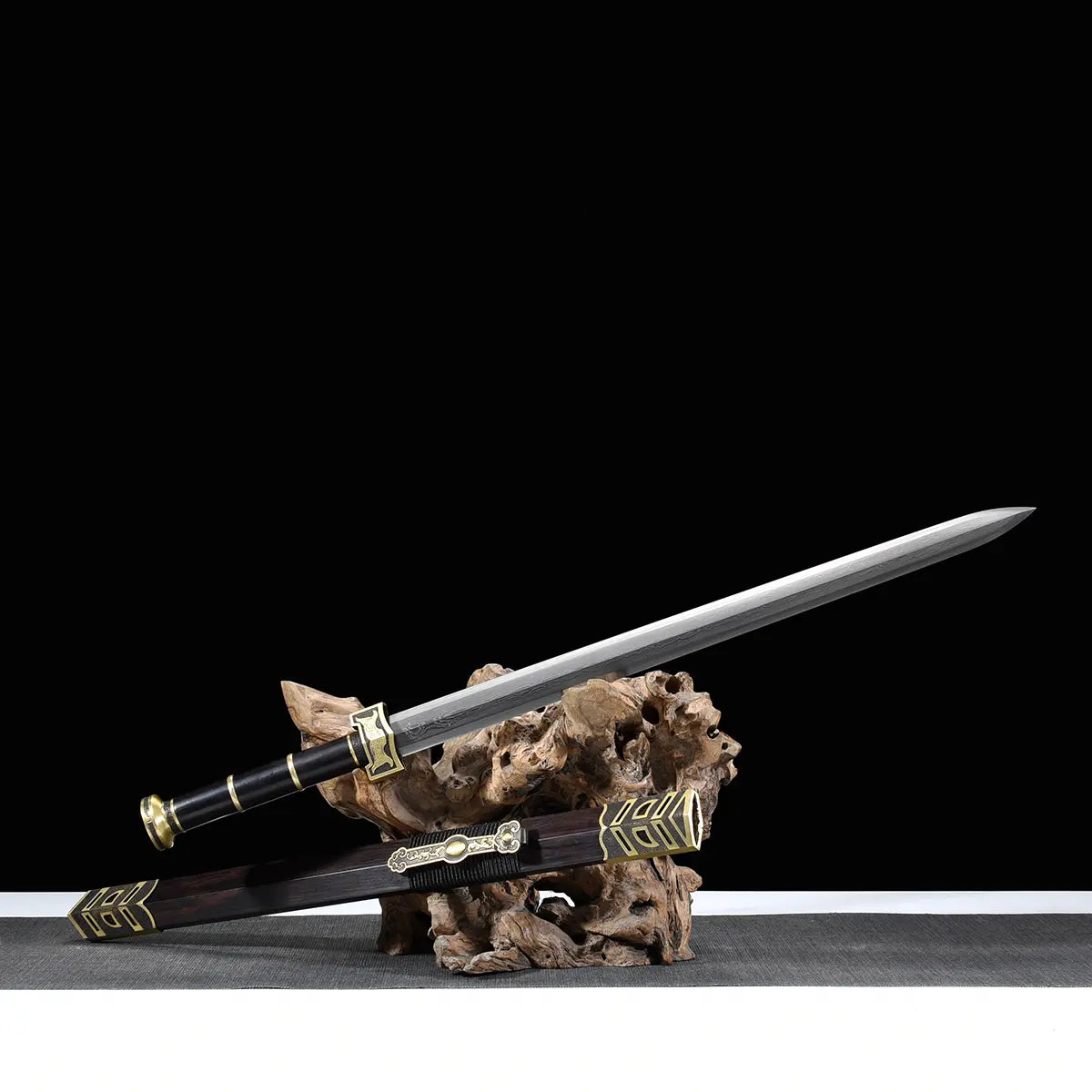 Épée chinoise Jian SHU SHENG présentée sur support en bois naturel, avec lame droite en acier plié Damas moderne, poignée noire, fourreau noir style ébène et garnitures en laiton doré, sur surface grise devant un fond noir.