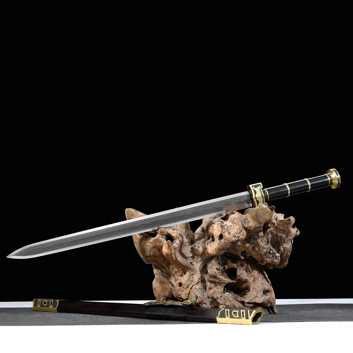 Épée chinoise Jian SHU SHENG présentée avec lame droite en acier plié Damas moderne sur support en bois naturel, fourreau noir style ébène posé en dessous, garnitures en laiton doré et fond noir avec surface grise.