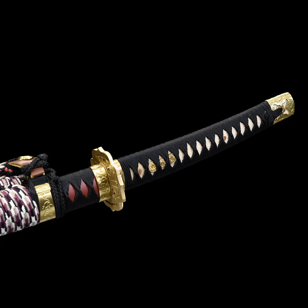 Close-up view of the Japanese tachi katana Taiyo Taisho photographed on a deep black background, showing the full handle with black tsuka wrapped in black ito over white ray skin panels, aligned gold-colored menuki along the grip, ornate gold fuchi and kashira, and part of the braided sageo cord near the base, studio lighting highlighting the handle length, texture, and traditional Japanese craftsmanship
