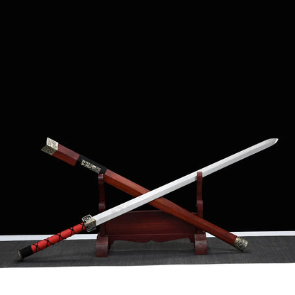 Épée chinoise Jian TIAN LONG présentée en diagonale sur un support d’exposition, avec lame droite en acier portant l’inscription chinoise « 龙泉剑 » signifiant Longquan Jian, fourreau en bois de rose, poignée rouge à cordage noir, garnitures métalliques décorées, fond noir et tapis gris visible en bas de l’image.