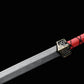Gros plan sur l’épée chinoise Jian TIAN LONG avec lame droite en acier gravée de l’inscription chinoise « 龙泉剑 » signifiant Longquan Jian, garde métallique décorée et poignée rouge entourée d’un cordage noir sur fond noir.