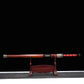 Épée chinoise Jian TIAN LONG présentée dans son fourreau en bois de rose sur un support d’exposition, avec poignée rouge entourée d’un cordage noir, garnitures métalliques décorées, fond noir et tapis gris visible en bas de l’image.