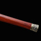 Gros plan sur le fourreau en bois de rose de l’épée chinoise Jian TIAN LONG, avec texture rouge-brun visible, garniture métallique d’extrémité décorée de motifs gravés et prise de vue rapprochée sur fond noir.