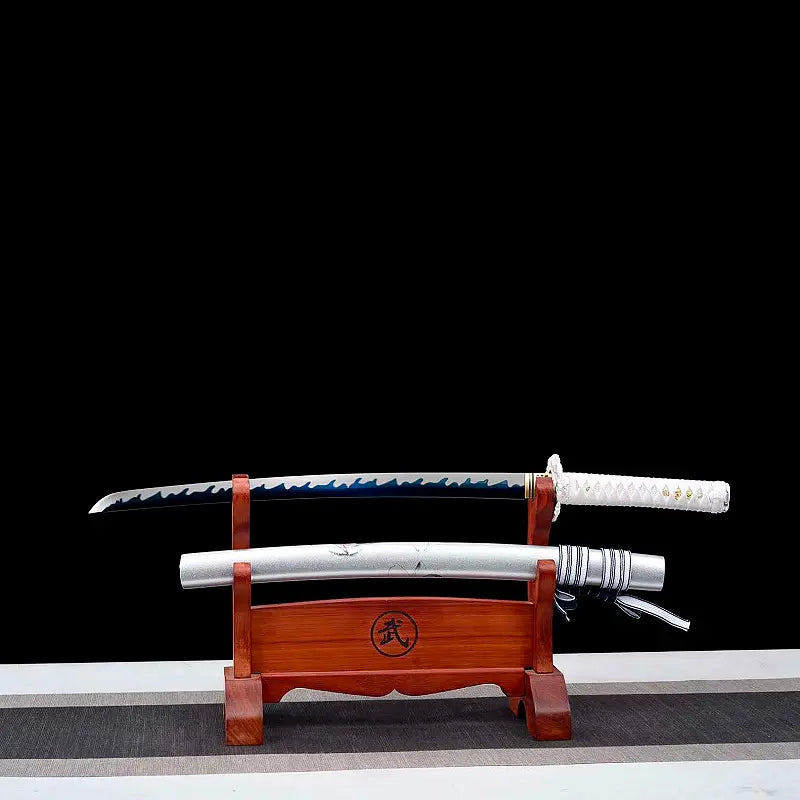 Wakizashi Aonami Nishikigoi dégainé : lame acier 1060 polie main avec hamon ondulé bleu, saya argentée posée en dessous sur un support en bois verni, tsuka blanche, scène sur fond noir — katana japonais wakizashi motif koi, finition satinée.