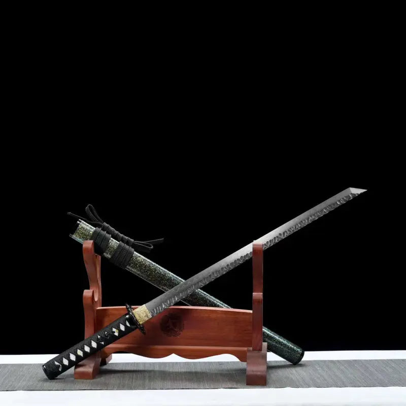 Wakizashi japonais Hoshizora présenté lame en diagonale sur support en bois, hamon réel et texture tsuchime visibles jusqu’au kissaki ; saya laqué vert nuit effet nashiji posé derrière avec sageo noir. Mise en scène sur tapis gris à bordure blanche, fond noir — sabre artisanal acier T10 trempe à l’argile, Blade Bushido.