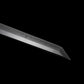 Gros plan du kissaki (pointe) du wakizashi japonais artisanal Aonami : lame T10 sans bohi, hamon bien visible jusqu’au yokote, poli miroir, photographié sur fond noir — trempe à l’argile, finition précise pour coupe nette.