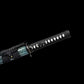 Gros plan du wakizashi japonais artisanal Aonami en acier T10 (hamon réel) : tsuka noire en ito, losanges de same blanche, tsuba ronde noire et habaki laiton, sageo noir sur saya nashiji bleu-vert, photographié sur fond noir.