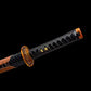Gros plan sur la tsuka du wakizashi japonais Kurochiku : tressage noir (ito), samegawa noire apparente avec menuki dorés, tsuba dorée motif bambou, aperçu du saya tressé noir avec laçage marron, sur fond entièrement noir.