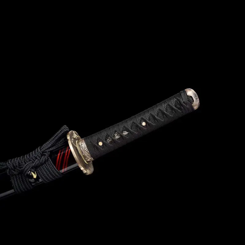 Gros plan du wakizashi japonais Renge no Reicha : tsuka au tressage noir (ito), tsuba en laiton motif lotus, fuchi gravé, saya noire laquée avec liserés pourpres et sageo noir, sur fond noir studio — sabre court artisanal acier plié damassé, Blade Bushido.