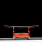 Vue d’ensemble du saya du wakizashi shirasaya artisanal Kuro Yōgan, posé seul sur un katanakake en bois teinte rouge, finition laque urushi noir-vermillon effet “lave”, fond noir avec liseré de sol gris/blanc en bas ; cadrage frontal, ambiance studio premium.