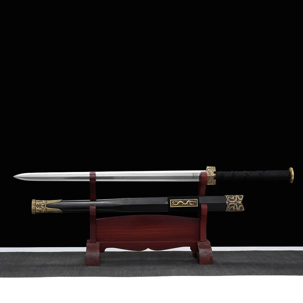 Épée chinoise Jian XUAN LONG présentée sur support en bois brun, avec lame droite sortie du fourreau noir, poignée noire tressée, garde dorée décorée et garnitures métalliques à motifs dragon.