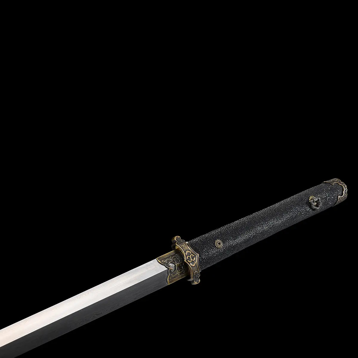 Vue rapprochée de la poignée noire texturée en galuchat d’une épée chinoise Jian YI XIN, avec garde traditionnelle en laiton vieilli et lame droite partiellement visible sur fond noir. L’image met en valeur les détails de la poignée, les ornements métalliques et la finition artisanale de ce Jian chinois de collection, Tai Chi et Wushu.