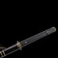 Gros plan sur la poignée noire texturée en galuchat d’une épée chinoise Jian YI XIN, avec garde en laiton vieilli, pommeau décoratif et partie du fourreau noir laqué visible. La prise de vue sur fond noir met en valeur les finitions traditionnelles, la texture de la poignée et les ornements métalliques de ce Jian chinois artisanal de collection, Tai Chi et Wushu.