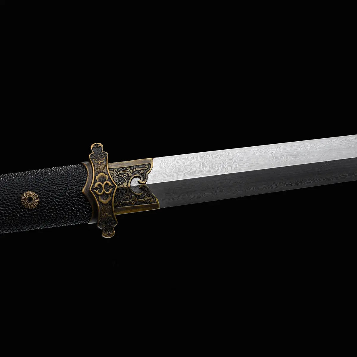 Gros plan sur une épée chinoise Jian YI XIN montrant la lame droite en acier Damas moderne multicouche avec motifs de forge visibles. La garde traditionnelle en laiton vieilli finement décorée est associée à une poignée noire texturée en galuchat. Fond noir mettant en valeur les détails de cette épée chinoise traditionnelle destinée à la collection, au Tai Chi et au Wushu.